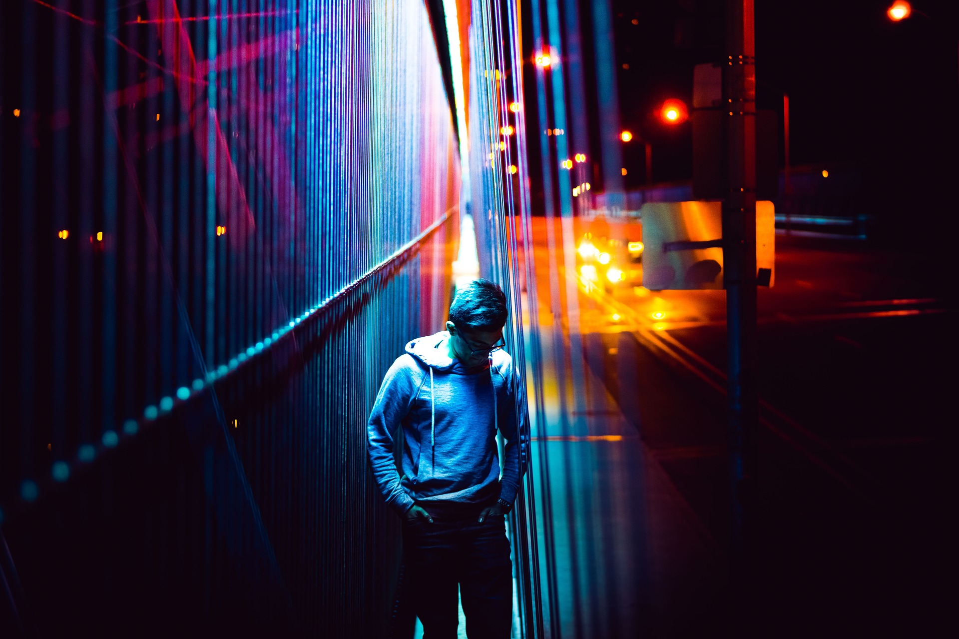 Gece vakti sokak lambalarıyla ışık oyunlarının arasında yürüyor.