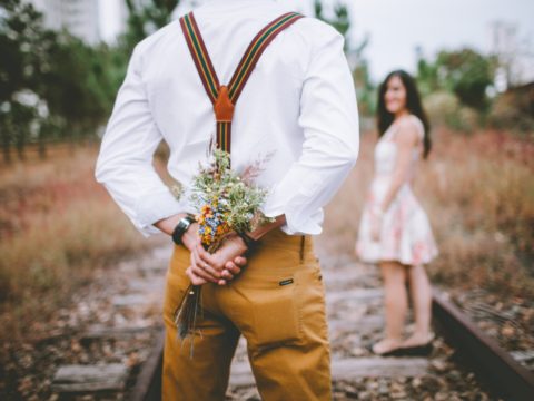 Adam, kadına sürpriz yapmak için arkasında bir demet çiçek gizliyor