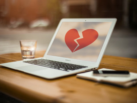 Bir laptop ekranında kırılmış bir kalp resmi var.