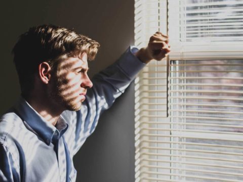 Depresyondan kurtulma yolu arayan düşünceli adam, pencereden dışarıya bakıyor.
