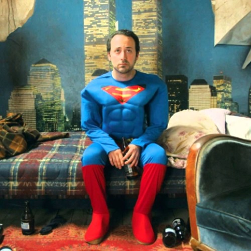 Tolga Çevik Süpermen kıyafetiyle oturuyor.