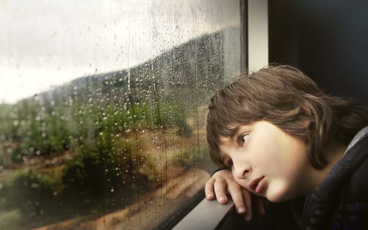 Bir çocuk trenin camından dışarı bakıyor.