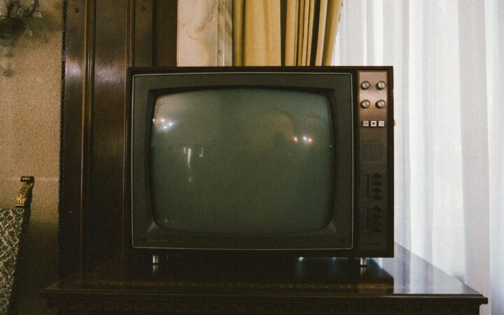 Kasvetli loş bir odada kapalı vaziyette duran eski tüplü bir televizyon.